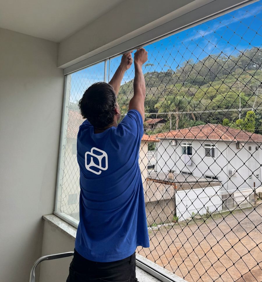 Instalador fixando rede de proteção em varanda