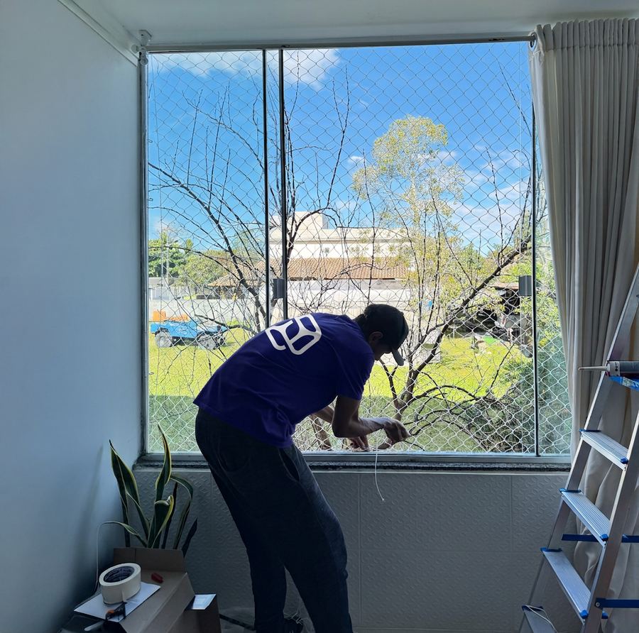 Instalador da equipe fixando rede de proteção